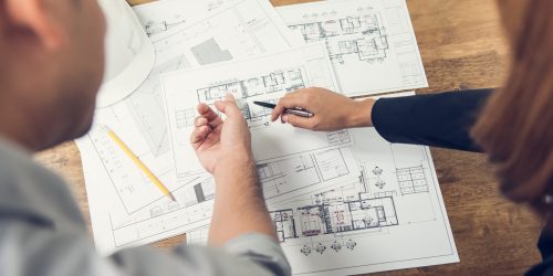 Engineer and architect discussing about blueprint layout design of  electricity plan at the construction site